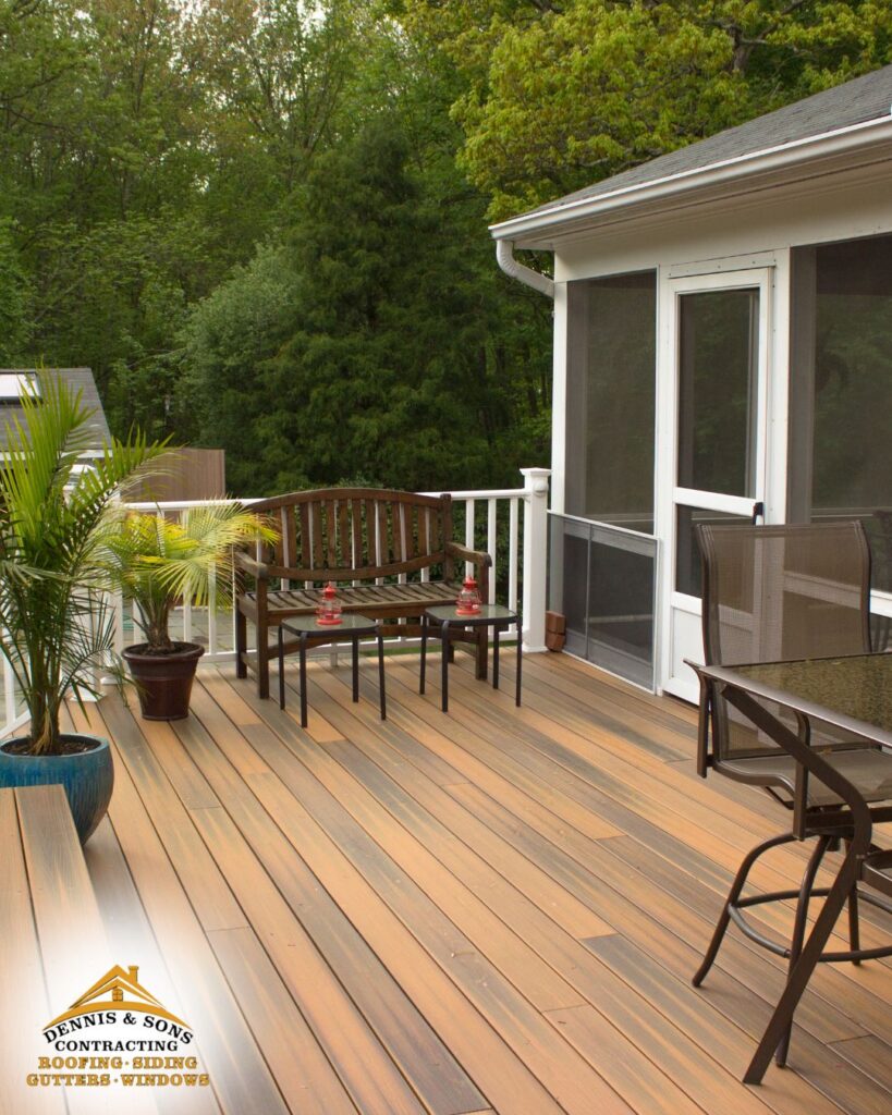 Spacious backyard wooden deck with bench seating, potted plants, and outdoor dining furniture next to a screened porch, surrounded by trees - dennisandsonscontracting.com
